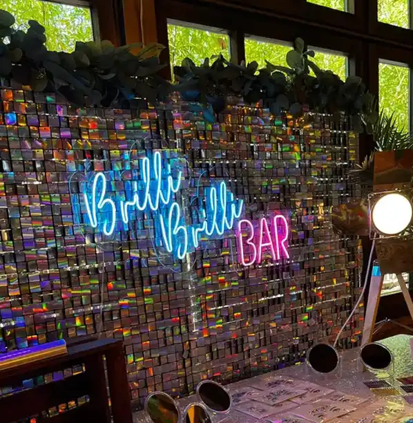 Brilli brilli bar. Letras de neon sobre pared decorada con brilli brilli