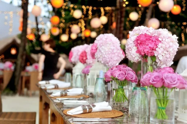 Decoración de eventos con flores rosas y luces colgantes creando un ambiente festivo y elegante único