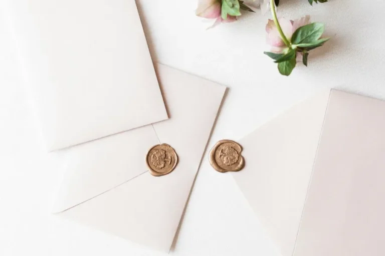 invitaciones de boda originales, sobre blanco con sello dorado sobre una mesa