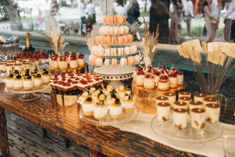 Candy bar de boda con macarons, vasitos de postre y dulces variados sobre mesa rústica decorada