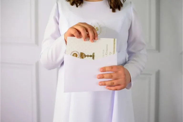 niña de comunión posando frente a photocall comunion con invitación en la mano